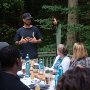 a man is standing at a table with people around him